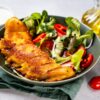 Close up of a plate with delicious breaded codfish with healthy salad